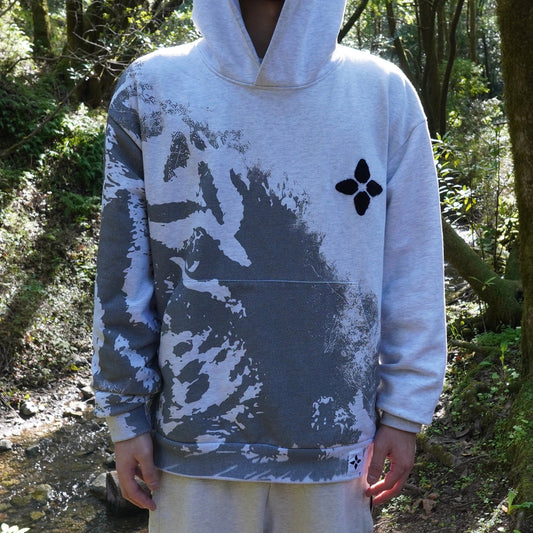 Person wearing a hoodie with a design in a forest setting